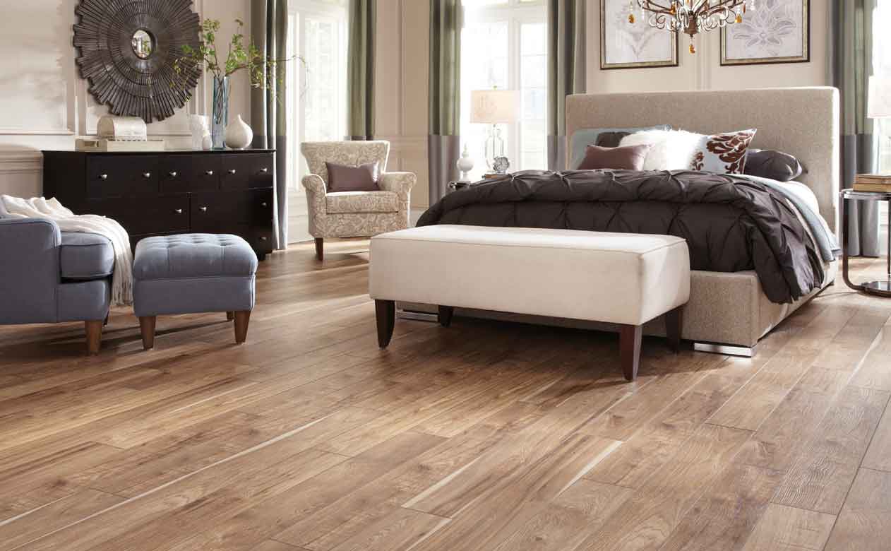 Cozy bedroom with light wood tile flooring, upholstered beige bed, and elegant decor in neutral tones.
